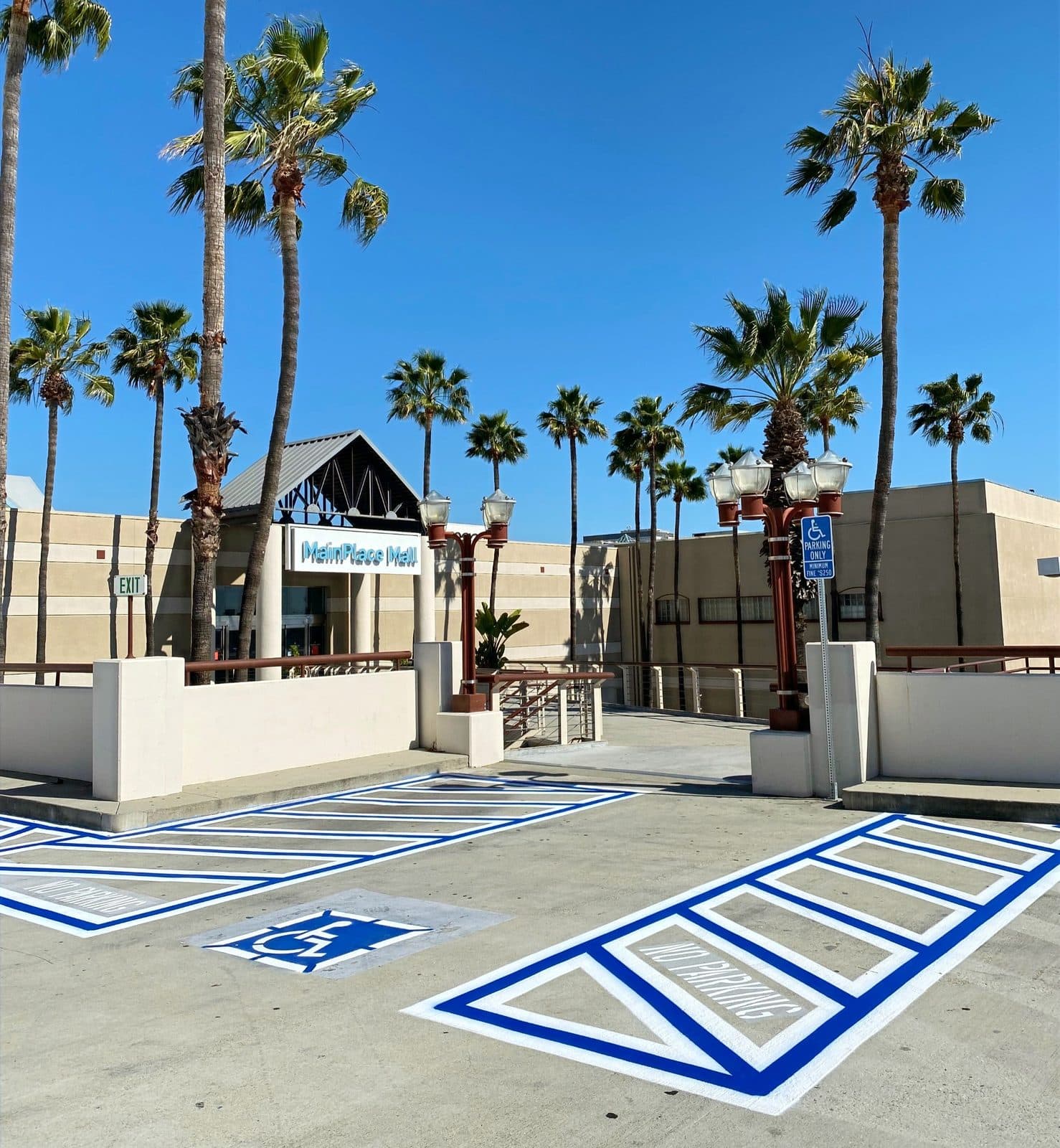 Freshly striped Southern California retail lot with ADA hatching and palms